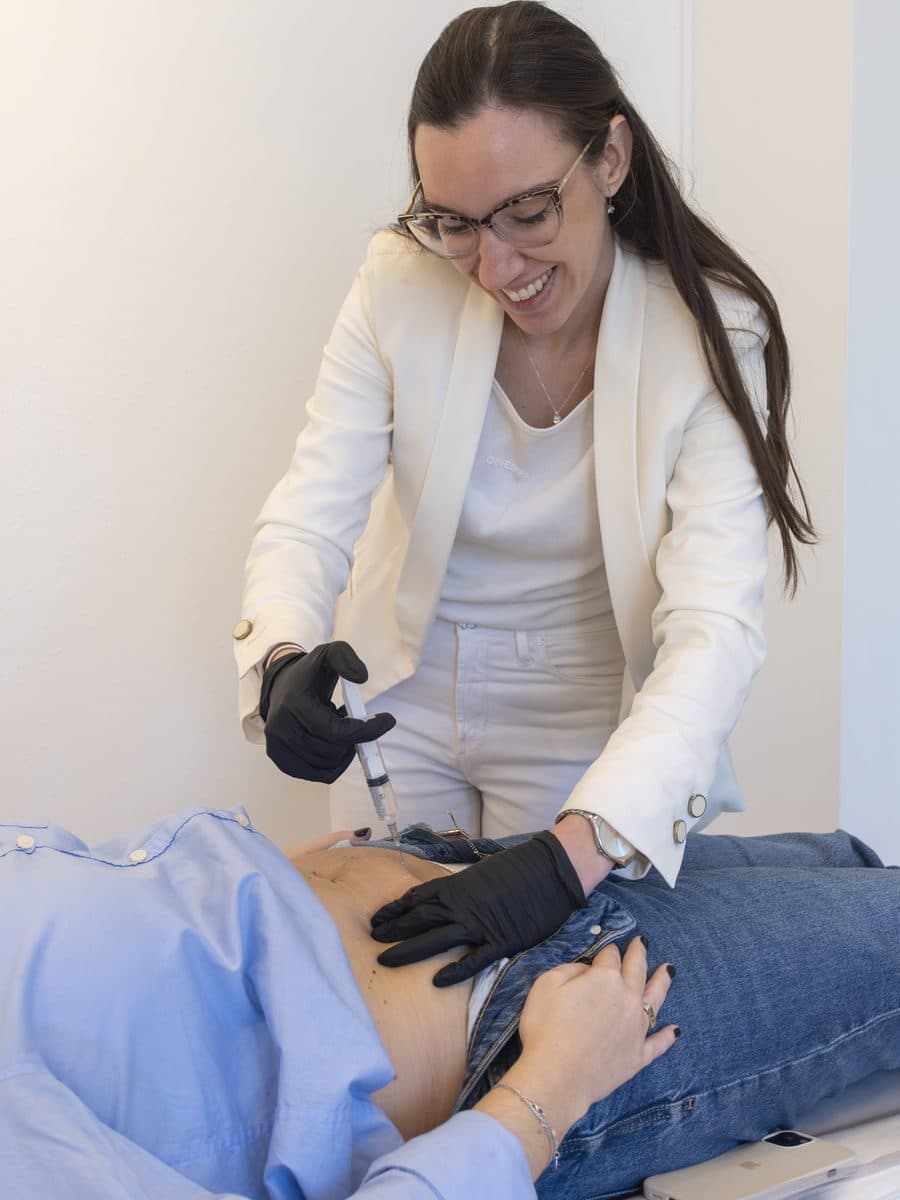 Profesional aplicando enzimas lipolíticas en el abdomen